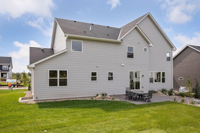 rear view of property with a lawn, a shingled roof, and a patio area