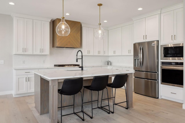 kitchen with premium range hood, light wood-style flooring, a sink, stainless steel appliances, and a breakfast bar area