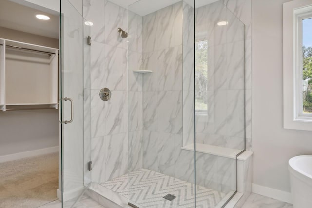 bathroom with marble finish floor, a stall shower, baseboards, and a freestanding tub