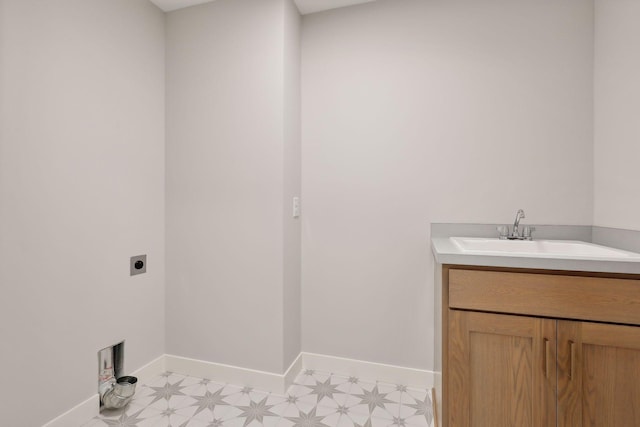 laundry room with light floors, electric dryer hookup, baseboards, and a sink