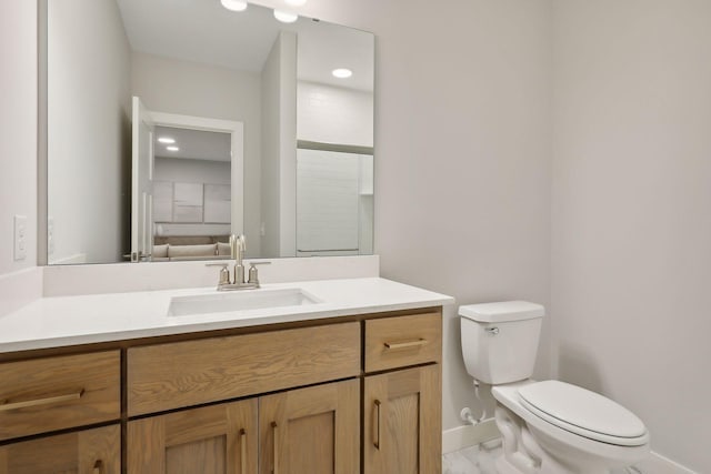 full bathroom with toilet, vanity, and baseboards