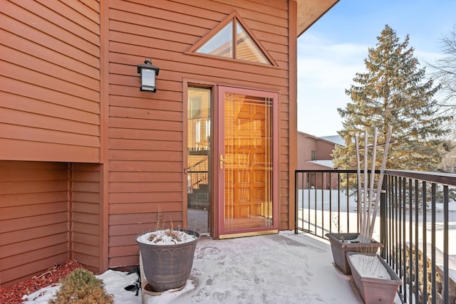 snow covered property entrance with a balcony