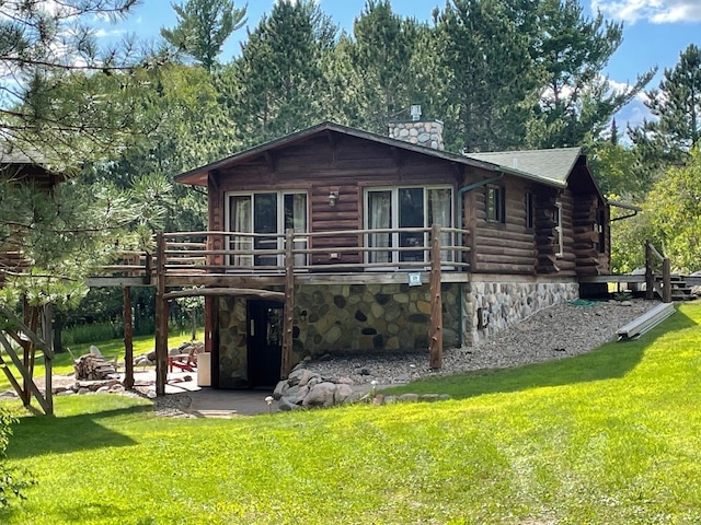 view of front facade featuring a chimney, a front yard, a patio area, log siding, and a wooden deck