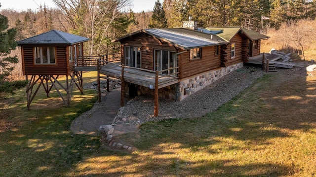 back of property featuring a wooded view, a yard, a chimney, and a wooden deck