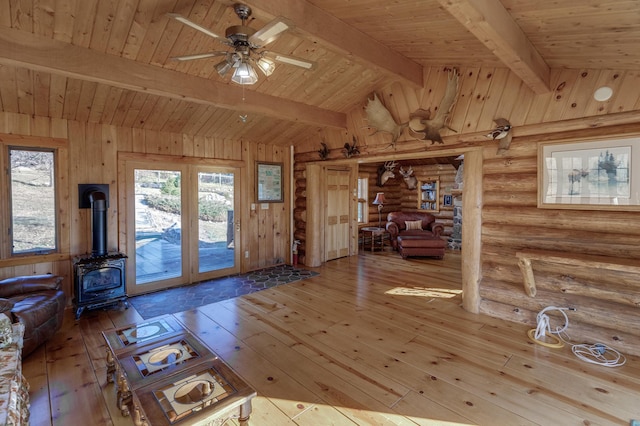 interior space with vaulted ceiling with beams, wood-type flooring, a ceiling fan, wood ceiling, and a wood stove