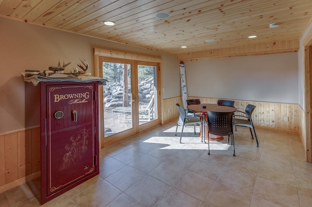 dining space featuring light tile patterned flooring, wooden walls, wood ceiling, french doors, and wainscoting