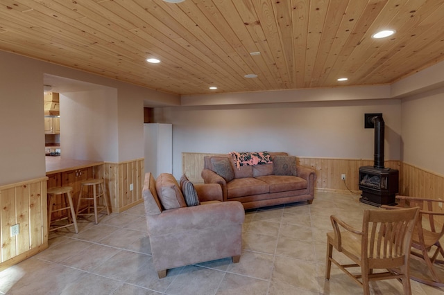 living area with a wainscoted wall, recessed lighting, wood ceiling, a wood stove, and wooden walls