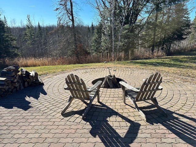 view of patio / terrace featuring a forest view and an outdoor fire pit