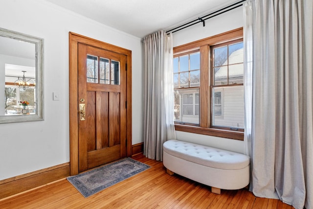 foyer featuring baseboards, an inviting chandelier, and wood finished floors