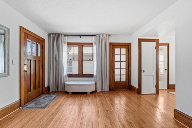 foyer entrance featuring light wood-style floors, baseboards, and a textured ceiling