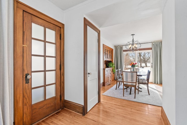 dining space with light wood-type flooring, baseboards, a chandelier, and crown molding