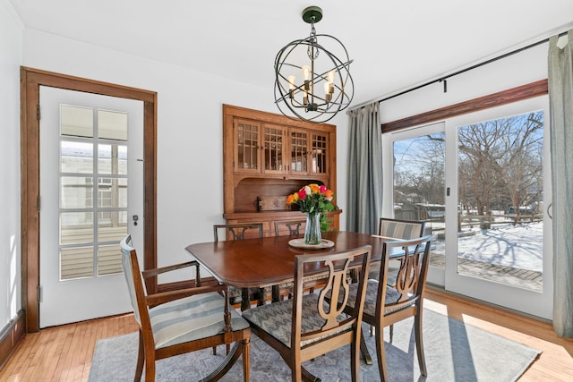 dining room featuring light wood-style floors, a healthy amount of sunlight, and an inviting chandelier