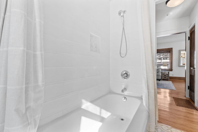 full bathroom with shower / tub combo and wood finished floors