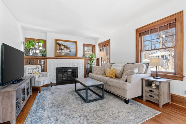 living room featuring a brick fireplace and wood finished floors