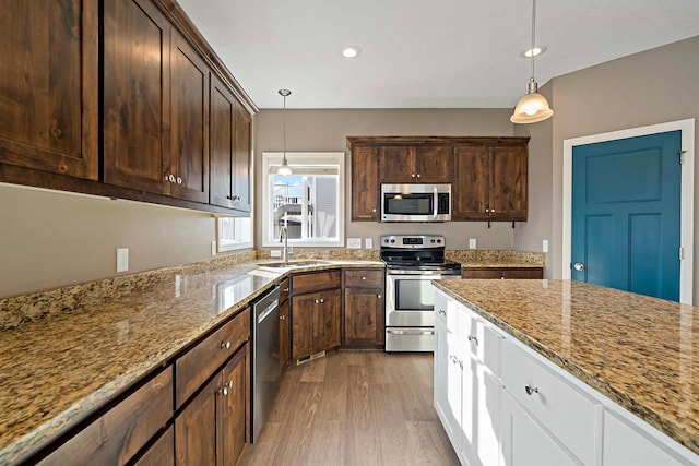 kitchen with light stone counters, decorative light fixtures, stainless steel appliances, and white cabinets