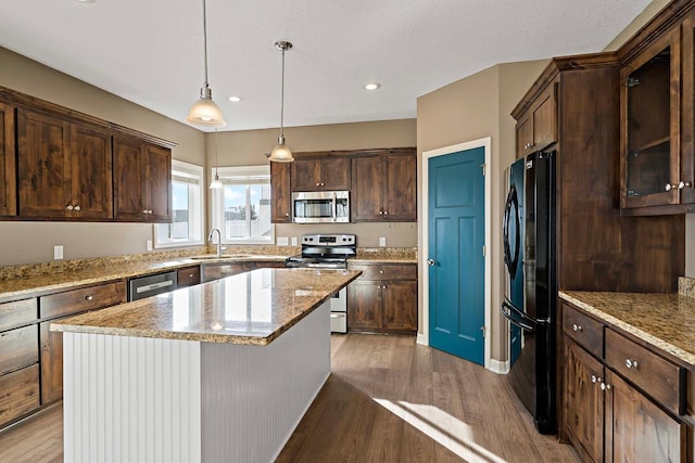 kitchen with dark brown cabinetry, stainless steel appliances, a center island, and wood-type flooring