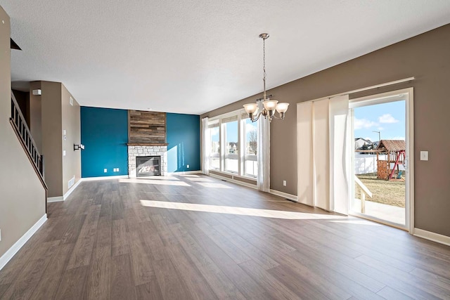 unfurnished living room with a notable chandelier, wood-type flooring, a fireplace, and a textured ceiling