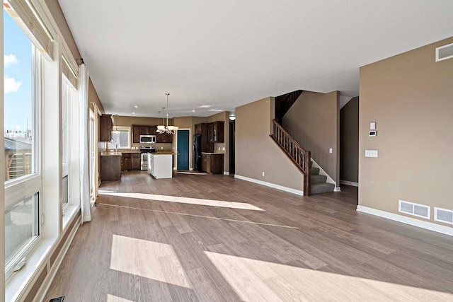 unfurnished living room featuring wood-type flooring and a notable chandelier