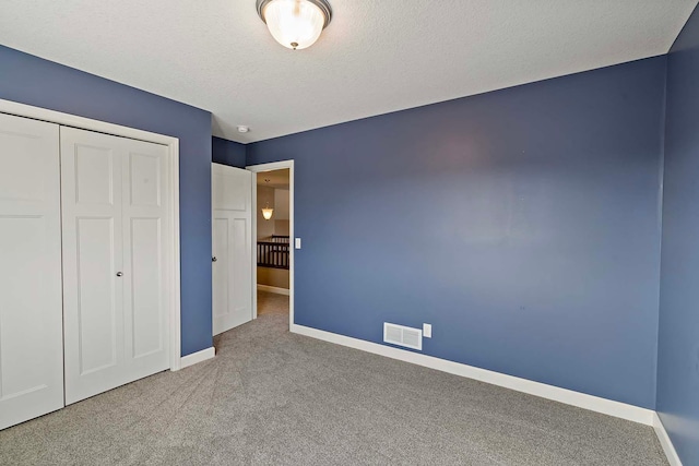 unfurnished bedroom with carpet flooring, a textured ceiling, and a closet