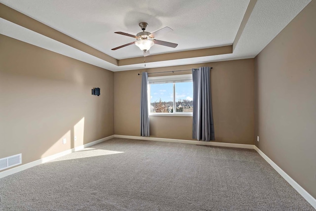 carpeted spare room with a raised ceiling, ceiling fan, and a textured ceiling