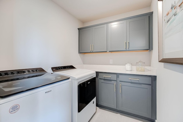 clothes washing area featuring cabinets and washer and dryer