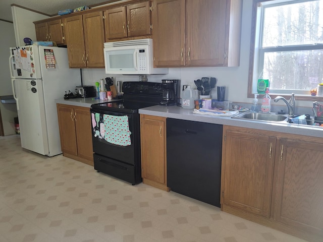 kitchen with brown cabinets, black appliances, light countertops, and a sink