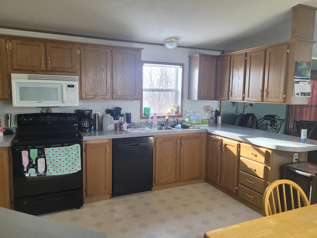 kitchen featuring light countertops, brown cabinetry, a sink, a peninsula, and black appliances