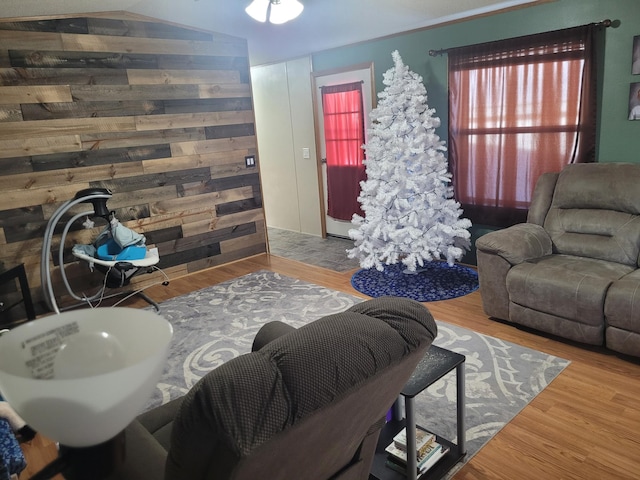 living room with wood walls, vaulted ceiling, and wood finished floors