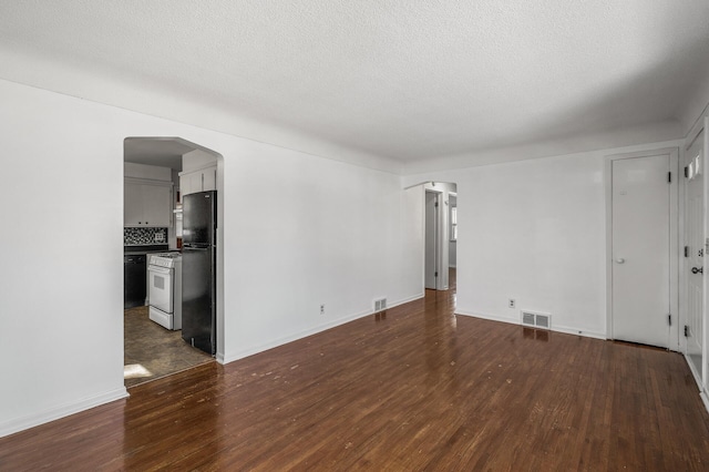 unfurnished living room with arched walkways, visible vents, and dark wood-type flooring