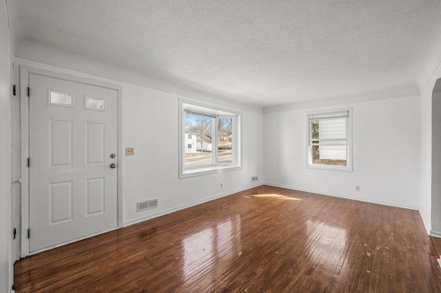 entryway featuring visible vents, baseboards, hardwood / wood-style flooring, arched walkways, and a textured ceiling