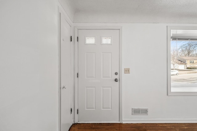 entryway featuring baseboards, wood finished floors, visible vents, and a textured ceiling