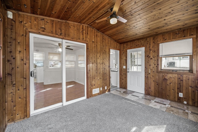 carpeted entrance foyer featuring a ceiling fan, visible vents, vaulted ceiling, wood ceiling, and wood walls