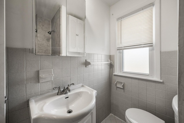 bathroom with tile walls, toilet, and a sink