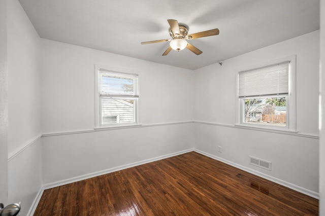 unfurnished room featuring visible vents, plenty of natural light, baseboards, and dark wood-style flooring