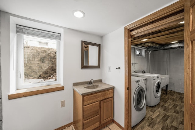 washroom with wood finished floors, baseboards, laundry area, a sink, and washing machine and dryer