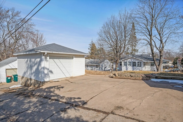 view of side of property featuring a detached garage, an outbuilding, roof with shingles, and driveway