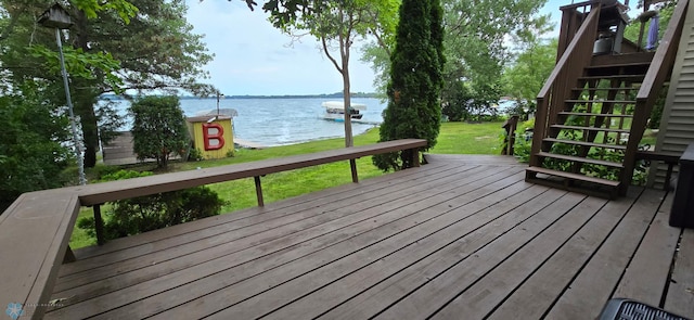 wooden terrace featuring stairway, a water view, and a lawn