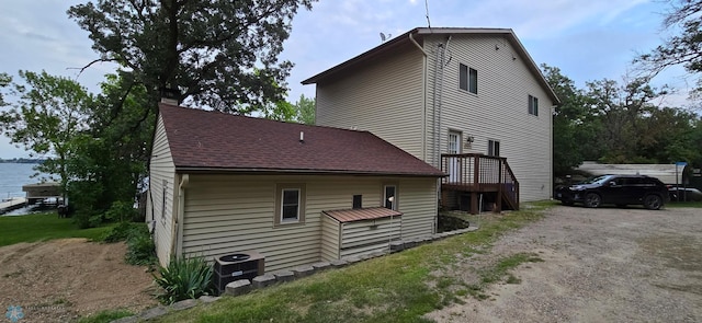 view of property exterior with driveway, central AC, and roof with shingles