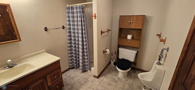 bathroom featuring vanity, a shower stall, toilet, and baseboards