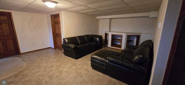 living area with tile patterned floors, a paneled ceiling, and baseboards