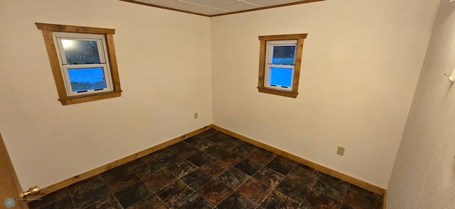 spare room featuring stone finish flooring and baseboards