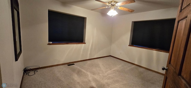 carpeted empty room featuring visible vents, ceiling fan, and baseboards