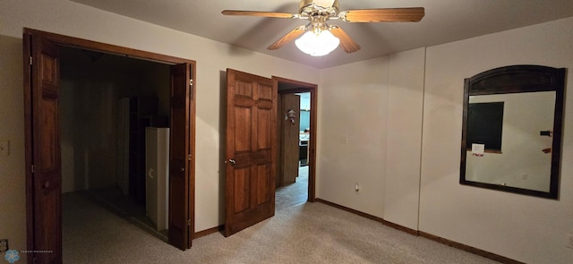 interior space featuring ceiling fan, baseboards, and light colored carpet