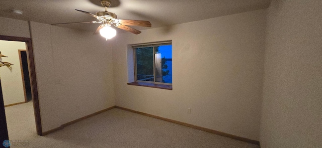 carpeted empty room with a ceiling fan and baseboards