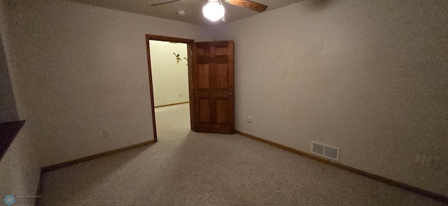 carpeted spare room featuring a ceiling fan, visible vents, and baseboards