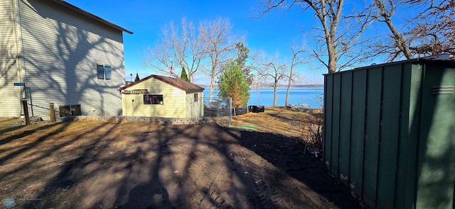 view of yard featuring a water view, an outdoor structure, and a storage unit