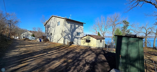 view of side of home featuring a water view, a storage unit, and an outbuilding