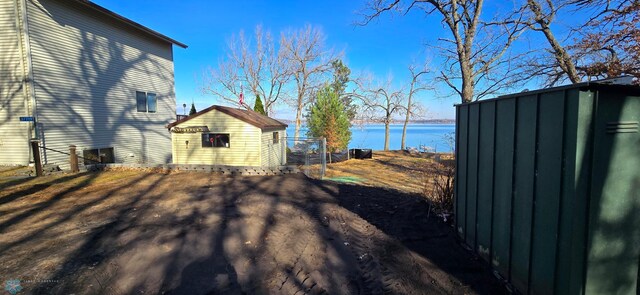 view of yard featuring an outbuilding, a water view, and a storage unit