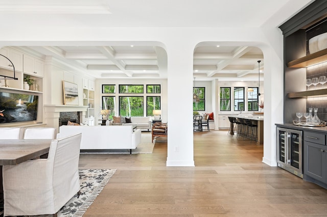 interior space featuring wine cooler, bar, a healthy amount of sunlight, and coffered ceiling