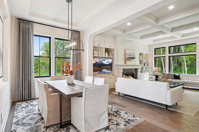 dining area featuring beamed ceiling, a healthy amount of sunlight, dark hardwood / wood-style flooring, and an inviting chandelier